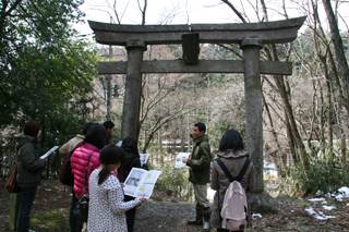 鳥居の下で話を聞く学生たち