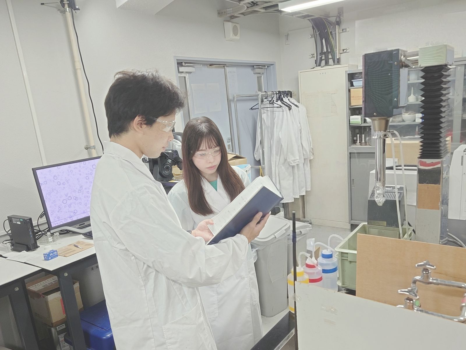 実験ノートを見ながら話す学生2名